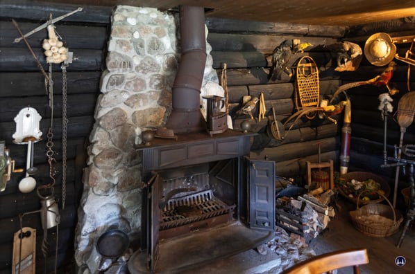 Ein eiserner Kamin mit verwinkeltem Rauchabzug gehört ebenso zu einem Blockhaus, wie Schneeschuhe oder ein paar Kochutensilien.