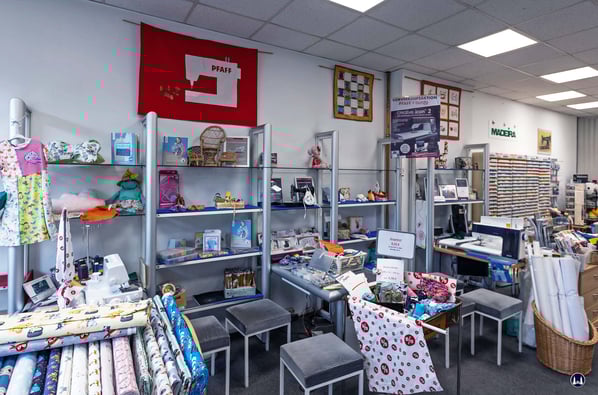 Blick auf zwei der an der Regalsystemwand befestigten Nähmaschinen - Vorführplätze.