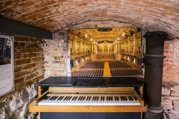 Stadtklause Bernburger Straße. Kellerraum mit Piano und Bild der zerstörten Philharmonie.