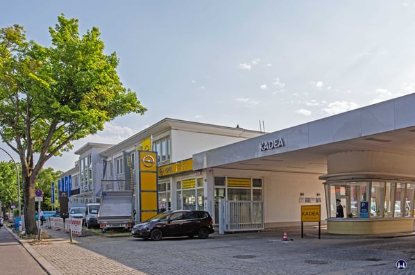 | Straßenfront des von Georg Stasch errichteten Verkaufsgebäudes an der Bessermerstraße (links) sowie die gleichfalls von ihm stammende Hofeinfahrt mit Pförtnerloge. Bis zum heutigen Tage werden hier Opelfahrzeuge, seit 1993 allerdings nicht mehr durch di