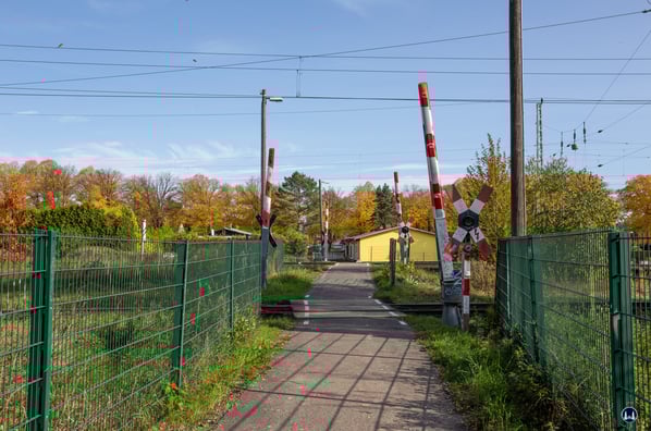 Blick in Richtung der Moselstraße und der Gaststätte "Schmidts" (gelbes Gebäude). Im Vordergrund die Schrankenanlage des Verbindungsgleises zum Berliner Außenring (auch "Potsdamer Kurve" genannt) dahinter die zweite Schrankenanlage der drei Gleise von und