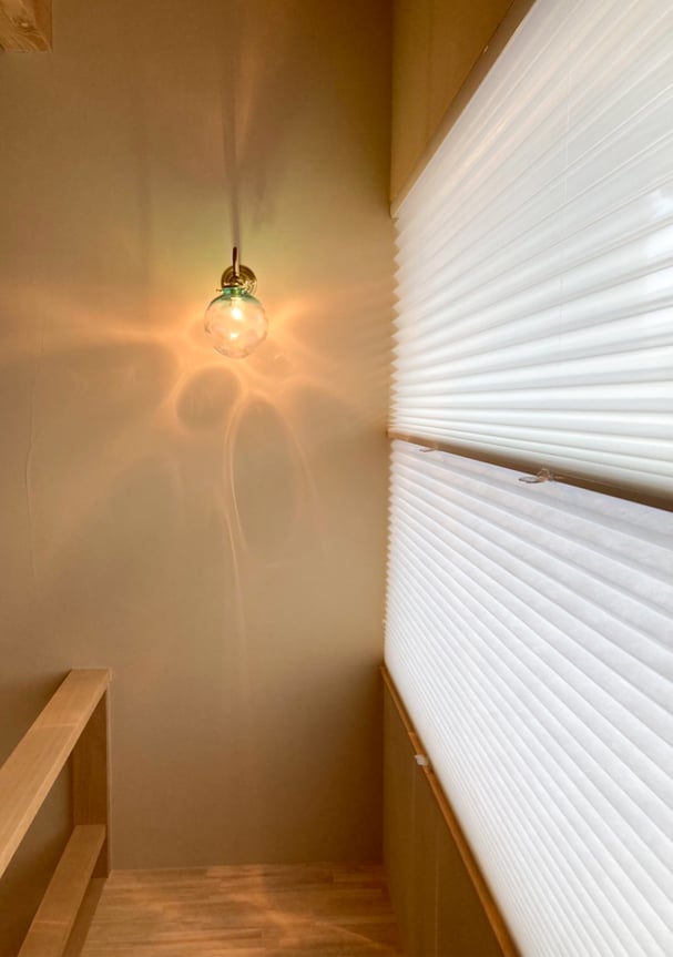 上レース・下ドレープのプリーツスクリーン。階段吹き抜けにやわらかな光を取り込む