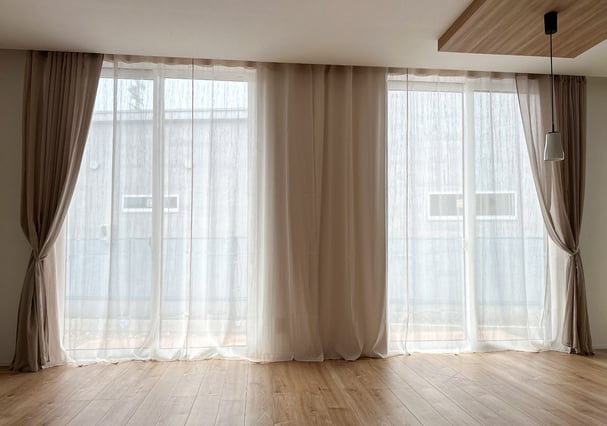大きな窓に二重のレースカーテンを設置。自然光をやわらかく拡散するリビングの様子