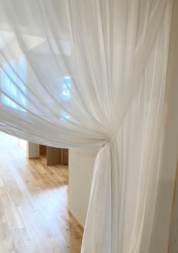 軽やかなシアーカーテンを束ねた様子。結ぶだけで整い、空間全体に動きと奥行きを生み出している。