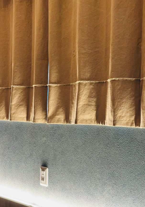 腰窓に天井付けで設置した帆布カーテン。しっかりとした生地感と落ち着いた色味が特徴