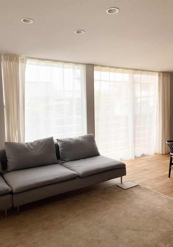 リビングの窓全体に取り付けられた天井付けカーテン。自然光がやわらかく差し込み、家具と調和している。