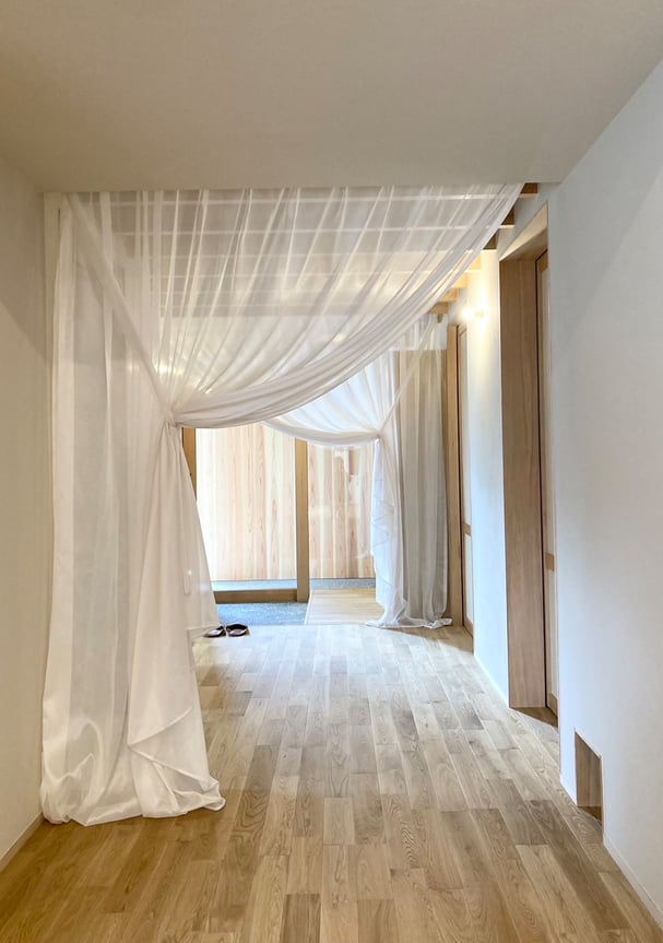 玄関からLDKへ続く通路に設置されたシアーの間仕切りカーテン。柔らかな透け感が空間を軽やかに演出している。