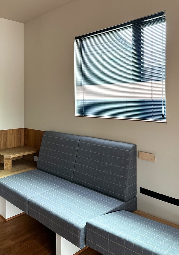 質の空間に設置されたオリジナルカラーのアルミブラインド。柔らかな光が差し込む様子