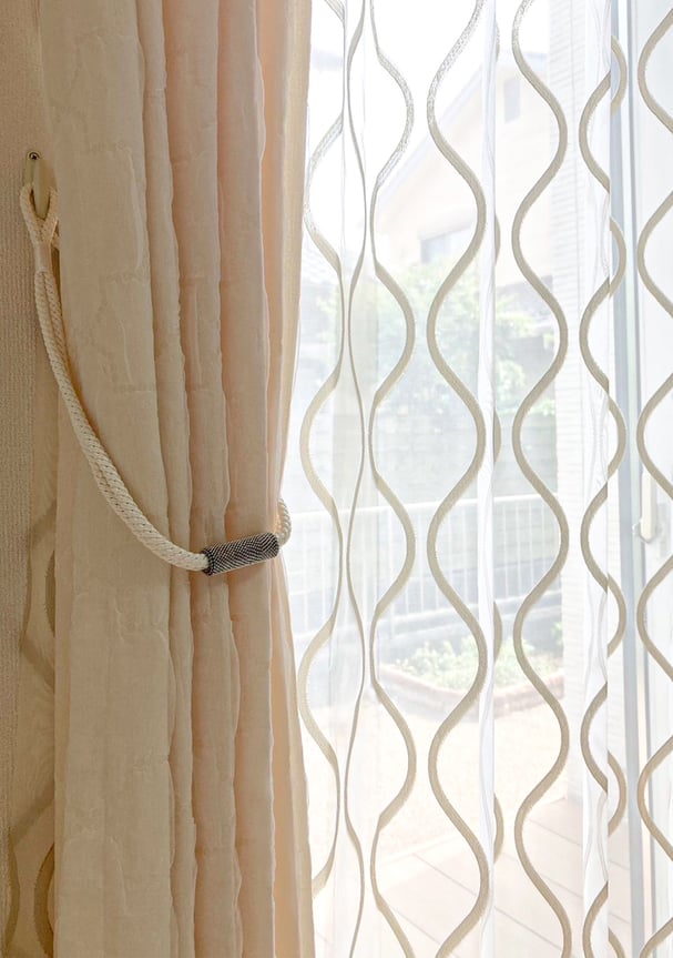 やわらかなジャカード生地のドレープカーテンと波模様のレースカーテン。ナチュラルな光が差し込む窓辺の様子。