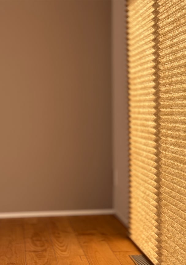 プリーツスクリーンを横から見た様子。プリーツの立体感と陰影が壁面に映り込む。