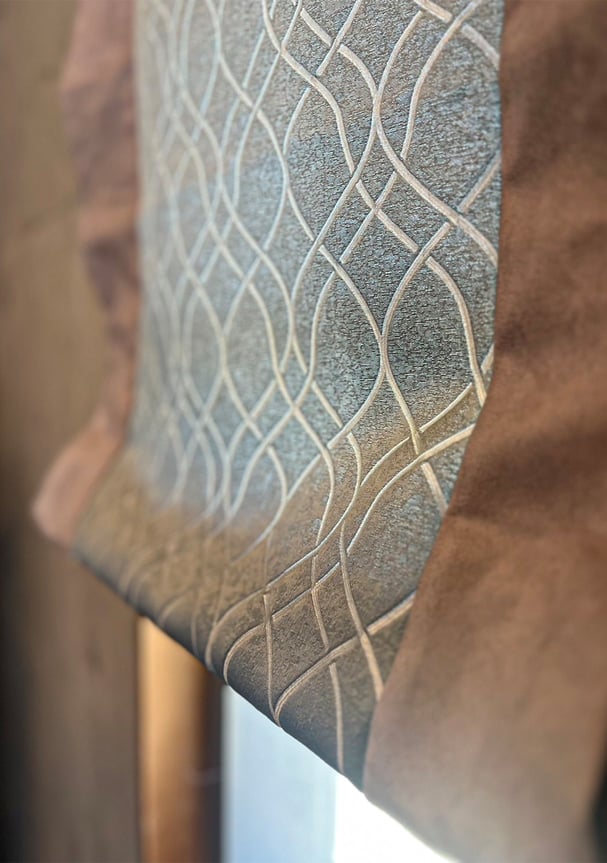 コンクリート壁の前に設置されたシェードカーテン。中央には幾何学模様の生地を使い、両サイドを無地で切り替えたデザイン。