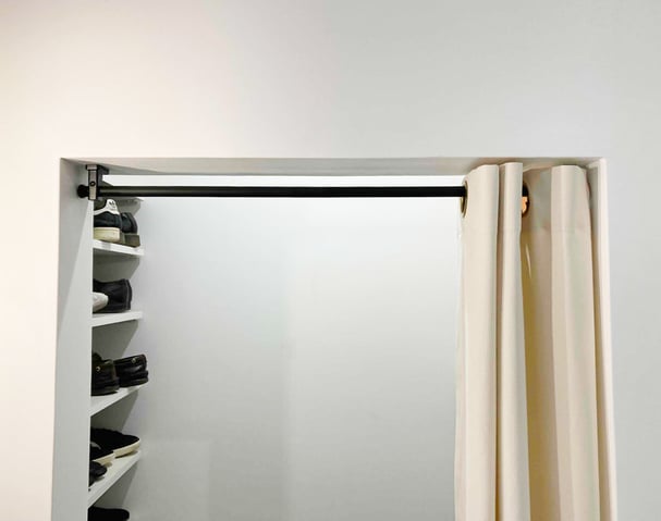 黒いアイアンパイプと真鍮ハトメを組み合わせたハトメカーテン。間仕切りとして設置された帆布が土間収納を隠している。