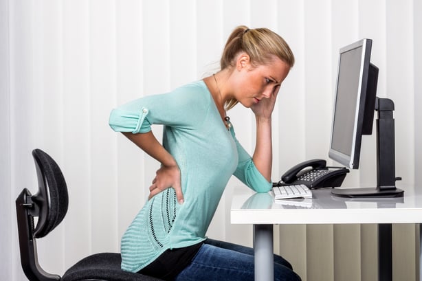 Woman with back pain at a computer.