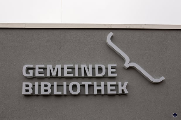 Beleuchteter Hinweis auf die Bibliothek an der Fassade.