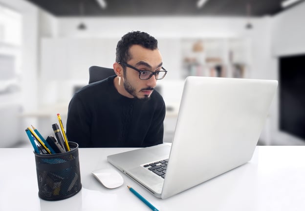 Mann mit Brille, der entsetzt in seinen Laptop schaut