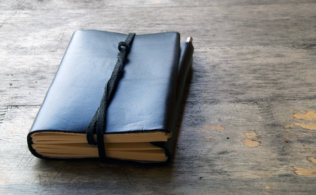 Schwarzes Tagbuch auf einem Holztisch