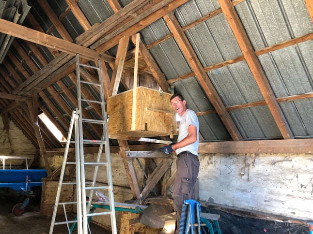 Dachstuhl der Sheune, ein Mann montiert einen großen Kasten aus OSB-Platten