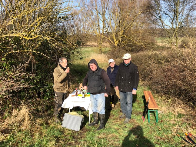 Helfer stehen an einem gedeckten Tisch auf einer Grasfläche