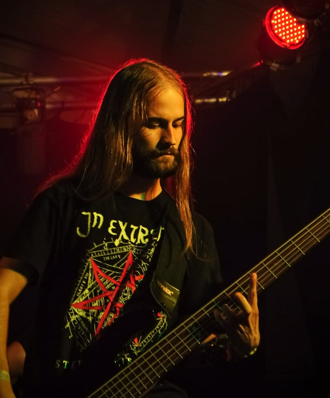 Musiker mit langen Haaren auf einer Bühne mit rotem Licht