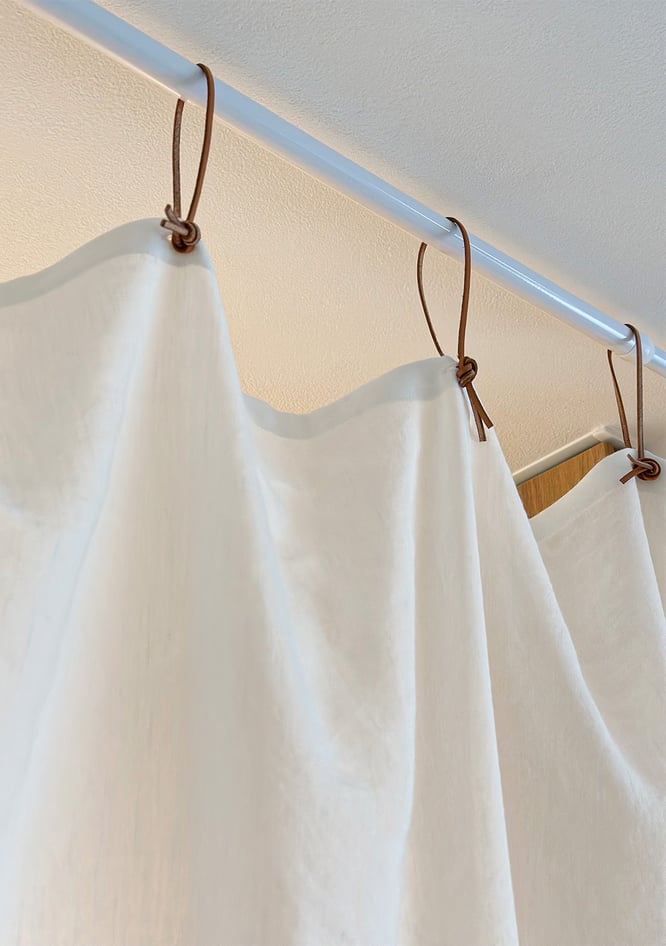 カーテンに革紐をつけ突っ張り棒でとめる画像