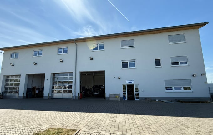 alt="Unser Firmengebäude mit 4 Rolltoren und der Eingangstür zum Büro"