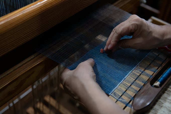 ▷細番手のリネンの経糸は切れやすいので補修しながら織り進む。