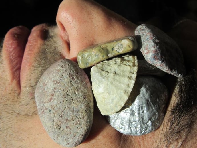 Gros plan sur le visage d'un homme d'on les yeux sont recouverts de pierres