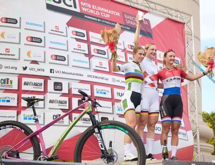 corratec Racingteam Fahrerin Marion Fromberger (Mitte) krönt ihr Jahr mit dem Gesamtsieg im UCI Mountainbike Eliminator Worldcup 2025. Im Vordergrund das Erfolgsrad: corratec Revo Bow SL Factory© corratec