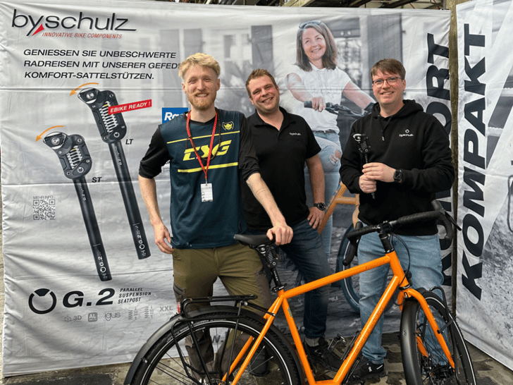 v.l.n.r.: Julius Oldehaver, Claudius Kleinsorgen und by,schulz Geschäftsführer Robert Koch bei Übergabe der G.2 ST Sattelstütze auf der Cycling World Düsseldorf 2025 am by,schulz Messestand