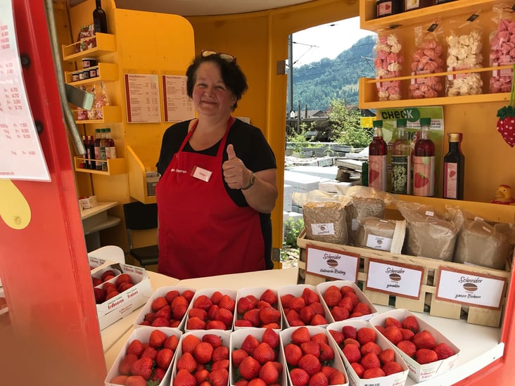 Verkaufsmitarbeiterin von Ritas Erdbeeren am Stand mit Erdbeeren und Kaffee.