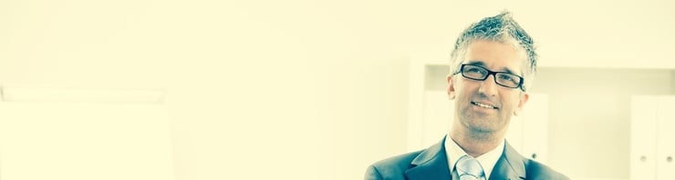 39jähriger, sportlich wirkender Mann in Anzug, weissem Hemd und Krawatte. Er hat graumeliertes Haar das er sehr jugendlich stylt und trägt Brille. Sein Blick ist konzentriert, nach oben gerichtet und freundlich.  Sein Hals und Kopf sind leicht schief.