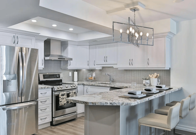 a cozy and well-lit kitchen with warm white cabinets, a spacious marble island, and modern appliances