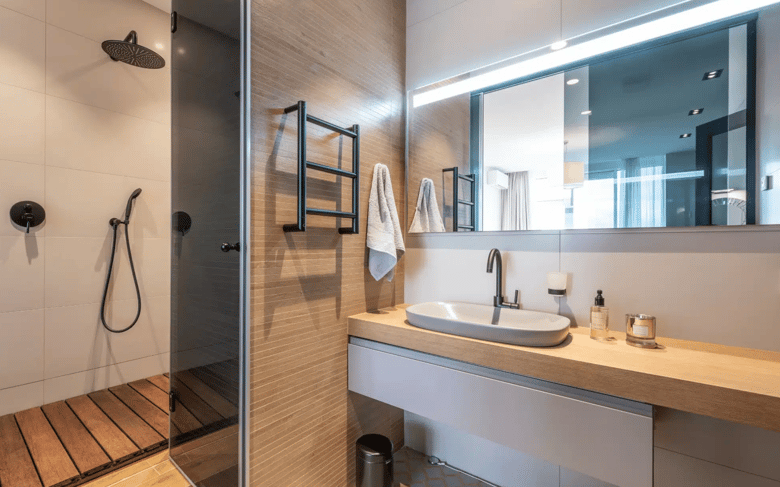 This bathroom features a modern and minimalist design with a sleek shower area, wooden accents, a wall-mounted sink, and stylish black fixtures, creating a clean and contemporary look.
