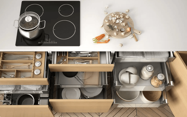 This modern, handle-free kitchen features a 40mm white stone benchtop, a black glass induction cooktop, and an array of drawers underneath, including a cutlery tray and large pots and pans drawers.