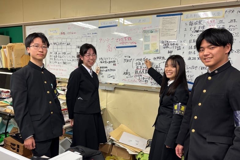 取材の日パソコン教室で活動していた部員の皆さん。新聞の企画を考えるホワイトボードの前で。