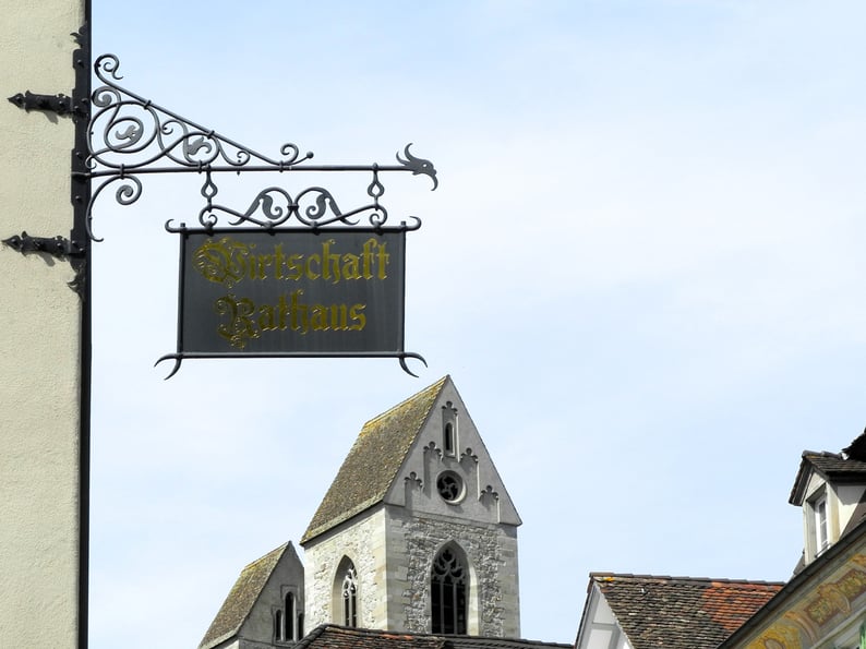 Nasenschild der »Wirtschaft Rathaus«, im Hintergrund die Stadtpfarrkirche