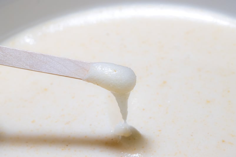 Miel de Trèfle Blanc crémeux de Nouvelle-Zélande dans un seau de 10kg avec une cuillère en bois et du Miel blanc qui dégouline dans le seau. 