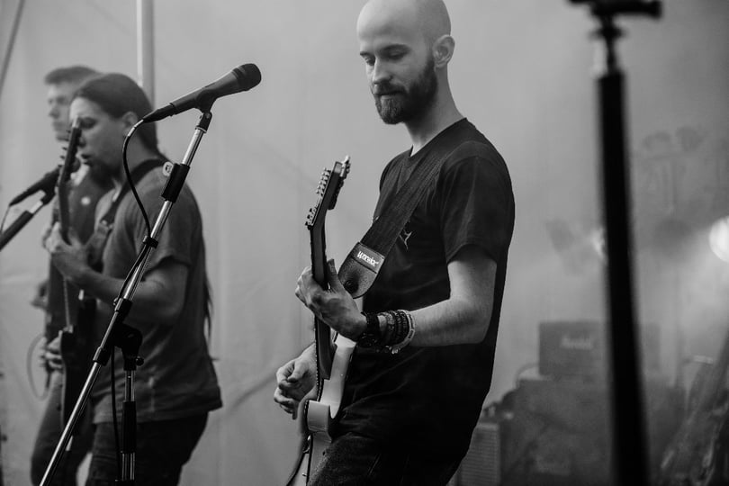 Musiker einer Metalband auf einer Bühne mit Gitarre und Mikrofonen