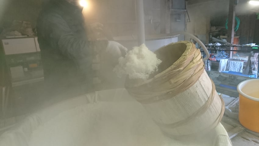 蒸した米を甑から取り出す。