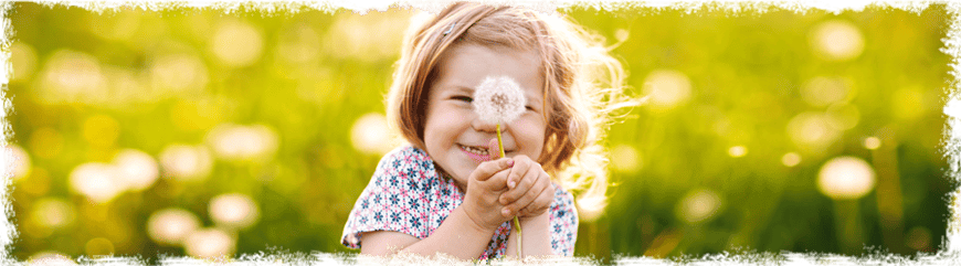 Mädchen mit Pusteblume auf einer Wiese, Glückskinder
