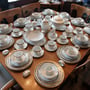 # 17 Un chic ensemble de vaisselle de 12 personnes pour les grandes occasions.Ce set de vaisselle est blanc orné de marine et d'or et comprend 10 morceaux par personne  (3 morceaux manquants seulement) et plusieurs pièces de services incluses. 