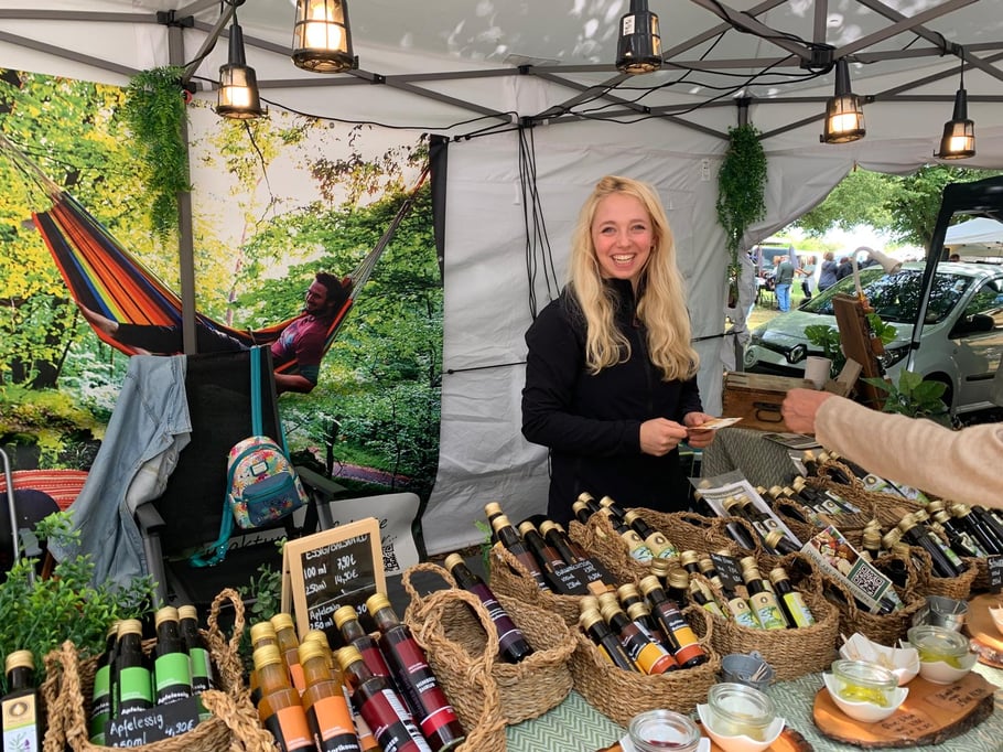 Geschäftsführerin Ann‑Kathrin Koch an einem Marktstand vor den Produkten der Mevlana Naturmühle.