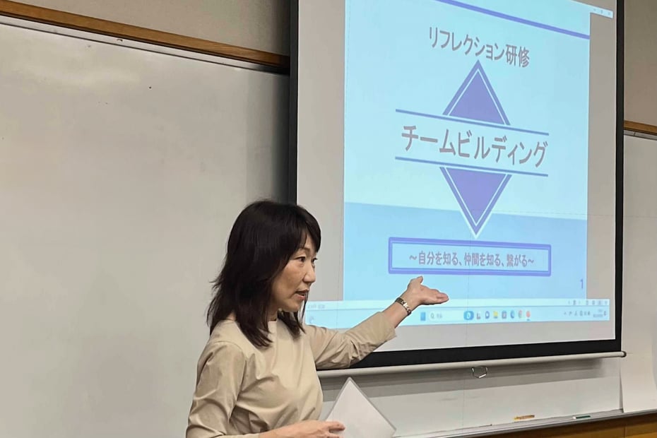 室内のスクリーンの前でワークショップの枠組みと目的を説明するプレゼンテーション
