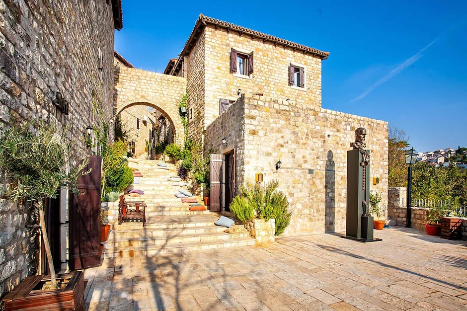 Historic stone buildings, monument of Miguel de Cervantes and charming stairway within Palata Venezia in Ulcinj's Old Town, featuring traditional Mediterranean architecture