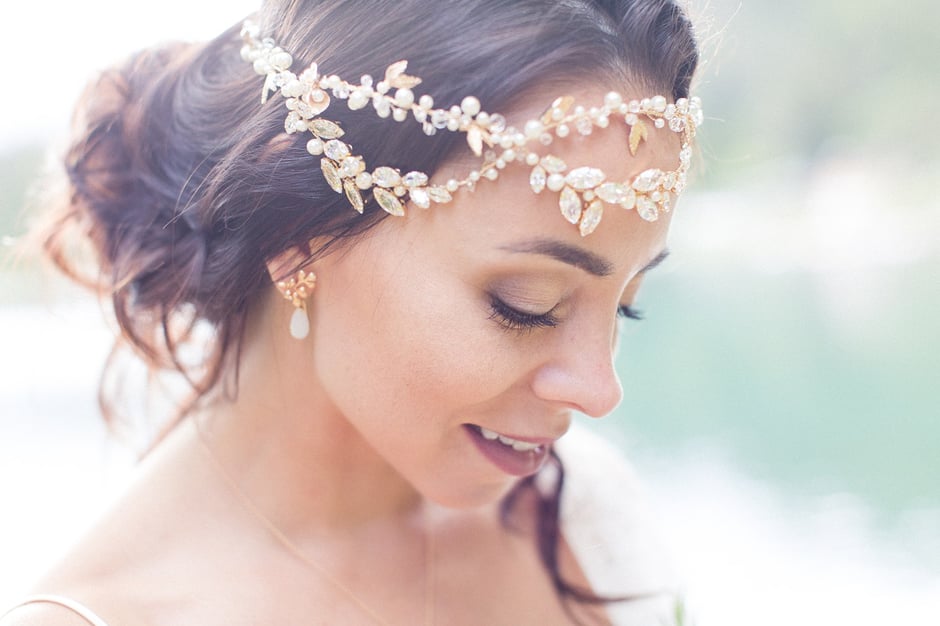 Dunkelhaarige Braut mit Haarschmuck und Ohrringen schaut nach unten, dezentes Make-Up