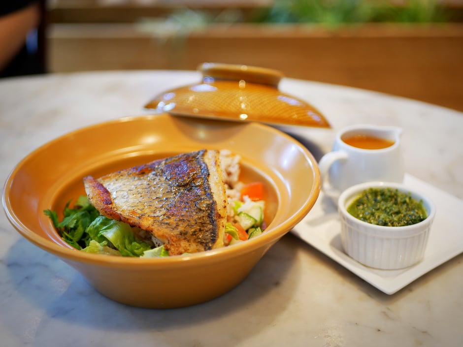 Wild barramundi brown rice bowl served with pesto sauce and garnished with shredded lettuce, red onion, avocado, lime wedges at The Living Cafe Singapore