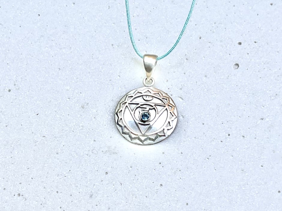 Handgefertigter Hals Chakra Anhänger mit Blautopas in Silber an einem hellblauen Band