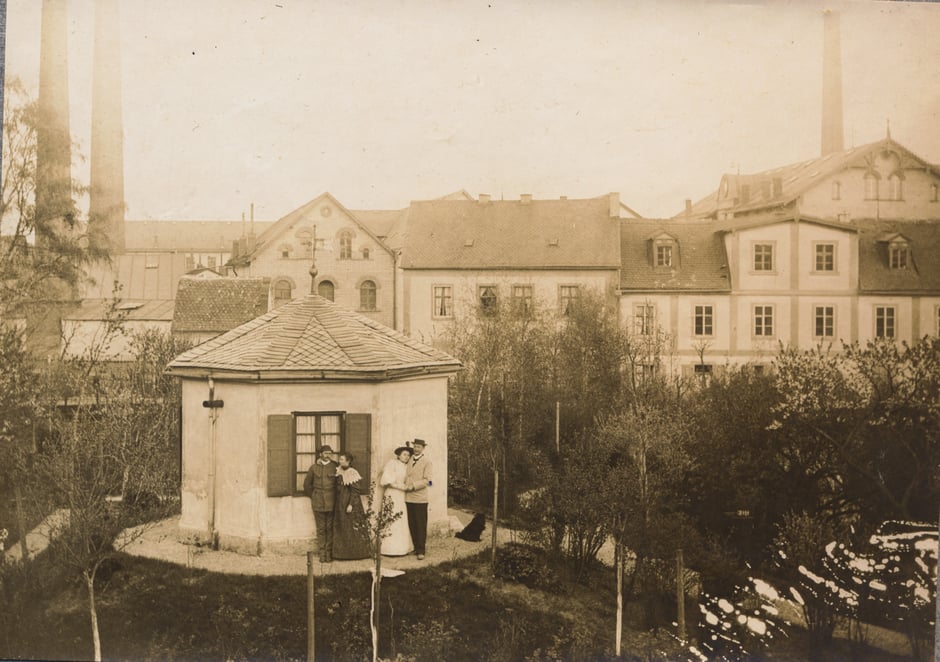 Vom "Pfarrhäusl" der Blick auf die Fabrik. Die Personen sind nicht bekannt. (vor 1903, da noch altes Wohn/Bürogebäude)