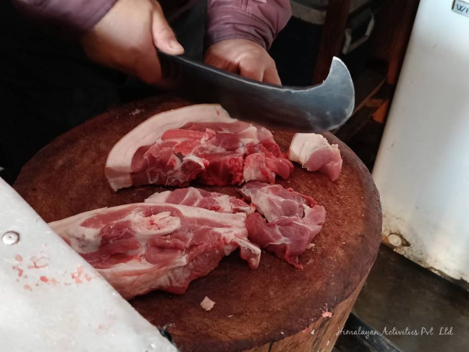 ネパールの肉屋で豚肉を切っています