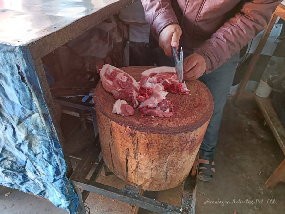 ネパールの肉屋で豚肉を切っています